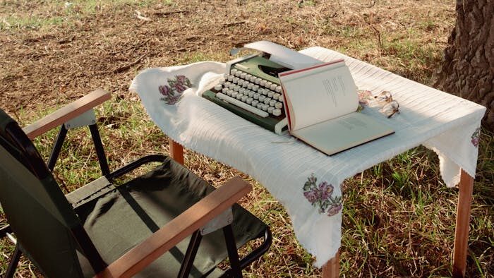 journey-02 Retro typewriter on a table under a tree, capturing a peaceful outdoor writing scene.